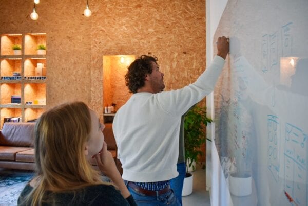 Foto van kristine, robert en reinoud op het kantoor van Brthrs. Terwijl ze tekenen op een whiteboard