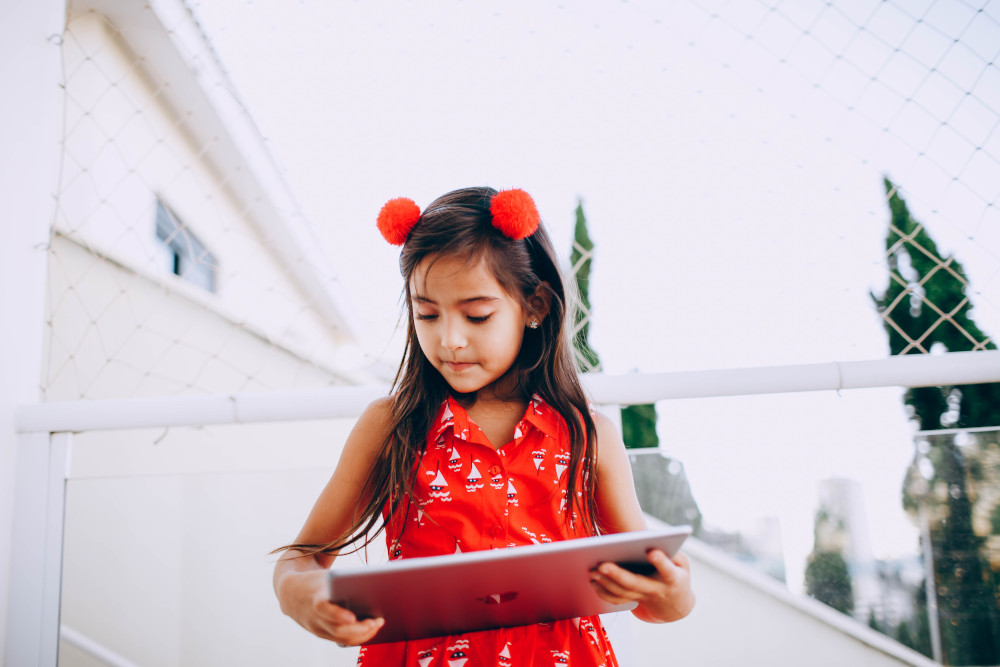 Girl with red dress uses a tablet